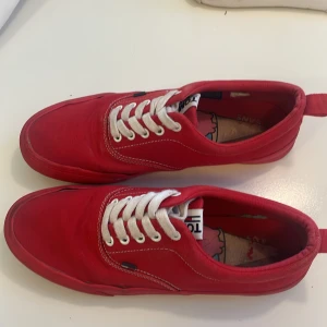 Röda Tommy Hilfiger sneakers - Säljer ett par röda Tommy Hilfiger sneakers i canvas med vita snören och kontrastsömmar. Skorna har en klassisk låg profil och platt sula. Perfekta för dig som vill sticka ut med färg och stil.