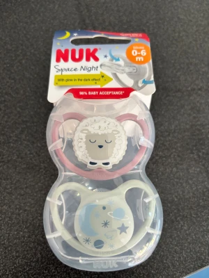 NUK Space Night 0-6m - NUK Space Night napp för 0-6 månader, med glow in the dark-effekt. Säljs i originalförpackning, helt ny och oanvänd. BPA-fri silikon, tillverkad i Tyskland. Söt design med får och rymdmotiv, perfekt för natten. Helt nyköpt men köpte för många! 