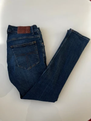 Tiger Of Sweden Jeans  - Snygga mörkblå jeans från Tiger Of Sweden med klassisk femficksdesign och bruna kontrastsömmar. Jeansen har en rak passform och är tillverkade i mjukt denimtyg som sitter skönt hela dagen. L30