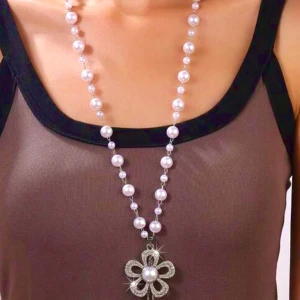 Långt glittrande pärlhalsband med blomma - .