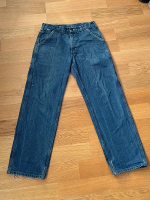 Blå Carhartt jeans med raka ben -  blå jeans från Carhartt. Straight fit, hyfsad baggy passform och praktiska fickor lite slitna här och där men jävligt slitstarka.