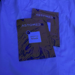 Astomed Whitening Mask ansiktsmask - 50 för båda. Astomed Whitening Mask är en ansiktsmask i smidigt engångsförpackning. Masken är framtagen för att ljusa upp hudtonen och ge glow. Förpackningen är gul med blå marmorering och vit etikett. Innehåller ingredienser som hyaluronsyra och växtextrakt.