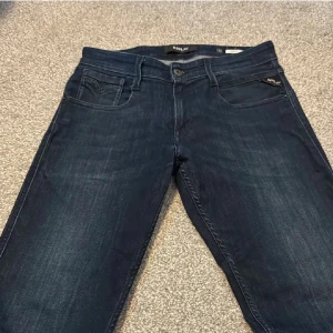  Replay jeans  - Säljer ett par mörkblå jeans från Replay med klassisk femficksdesign och diskret Replay-logga på fickan. Jeansen har raka ben och är tillverkade i mjukt denimtyg som sitter skönt hela dagen. Perfekta för dig som gillar en stilren look.