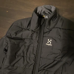 Svart pufferjacka från Haglöfs M - Svart pufferjacka från Haglöfs i storlek M. Jackan har hög krage, hel dragkedja och två sidofickor med dragkedja. Materialet är lätt och quiltat, med Pertex-tyg för extra funktion. Perfekt för kalla dagar och outdoor-aktiviteter. Perfekt för vintern! Har haft den i 2 månader.Helt ny!!!