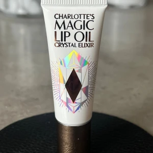 Charlotte Tilbury Magic Lip Oil - Njut av supermjuka, lena läppar med Charlotte Tilbury Magic Lip Oil Crystal Elixer, ett läppbalsam som hjälper till att vårda huden samtidigt som det ger glans och fyllighet. En vitamin- och aloe vera-berikad formula som återfuktar och förbereder läpparna för applicering av läppstift. 