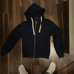Marinblå hoodie från Polo Ralph Lauren - Säljer denna Ralph Lauren zip hoodie då den inte passat mig på ett bra tag bara hängt i min garderob, otroligt bra skick använde inte den så mycket. Är M men passar också S. Skicka gärna vid intresse!