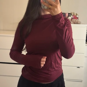 Vinröd långärmad polotröja - Snygg vinröd polotröja med lång ärm och tight passform. Tröjan har en enkel design utan mönster och är gjord i mjukt bomullsmaterial som känns skönt mot huden.