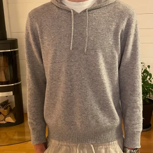 Grå hoodie i kashmir från Sayless - Mjuk och lyxig grå hoodie från Sayless i kashmir. Tröjan har huva med snörning, ribbade muddar och långärmad passform. Perfekt för dig som gillar stilren och chill look. Snygg att matcha med både jeans och mjukisbyxor. Säljer hoodien då den har blivit för liten helt enkelt. Inga synbara defekter utan i mycket god skick. Hör av er om ni har några funderingar!