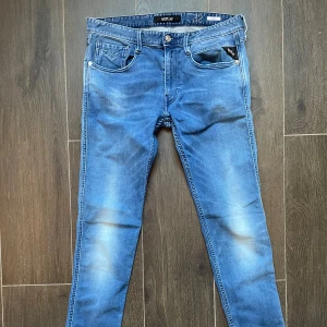 Replay Anbass blå - Snygga blå Replay Anbass slim fit jeans med klassisk femficksdesign och diskreta slitningar. Jeansen har normal passform och raka ben, tillverkade i mjukt denimtyg. Perfekta för dig som gillar stilrena och bekväma jeans med en modern look. Om du har frågor eller prisdiskutering så är det bara att skriva 😄