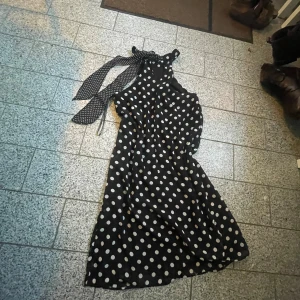 Svart prickig klänning Vero Moda - Supersnygg svart klänning från Vero Moda med vita prickar och knytband i halsen. Klänningen har en flowy passform och är ärmlös, perfekt skick, aldrig använd! 