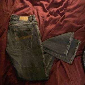Gråa Nudie Jeans w32 - Säljer ett par svarta jeans från Nudie Jeans med klassisk orange söm och broderad bakficka.  Den jag köpte byxorna sa att det var w34 men den sitter som w32