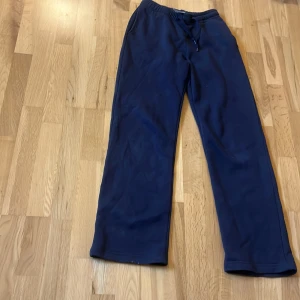 Marinblå mjukisbyxor från Gina Tricot - Säljer ett par marinblå mjukisbyxor från Gina Tricot, basically basics. De har normal passform, resår i midjan med snörning och raka ben. Perfekta för chill dagar och hänger snyggt på kroppen. 