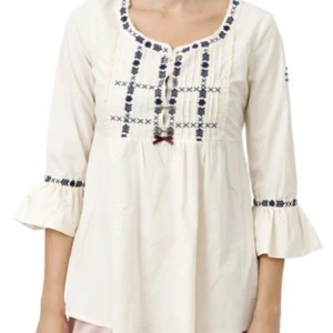 Vit broderad blus  - Säljer en vit blus med blå broderade detaljer och en liten rosett framtill. På ena armen sitter det en rosdetalj.