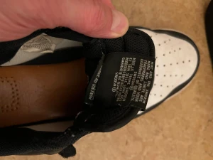 Nike Air Force 1 svartvita sneakers - Svartvita Nike Air Force 1 sneakers med klassisk låg siluett. Storlek: 44. Skorna har snörning, perforerad tå och platt sula. Ovandelen är i skinn och syntet, med tydlig Nike Swoosh på sidan. Perfekt för dig som gillar streetstyle och tidlös design.