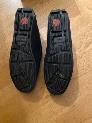 Mörkblå mockaloafers från Zeus - Snygga loafers från Zeus i mörkblå mocka med kontrasterande vita sömmar. Skorna är använda 1 gång!! Hade dom till min bal och sen har dom bara stått. Köpte dom för 1100kr!! Storleken är 43 men passar som 44