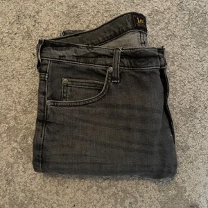 Jeans från Lee - Snygga mörkgrå jeans från lee i storlek 32/32. Byxorna är använda ett par fåtal gånger och är slim i modellen. Skicket är 8/10. 