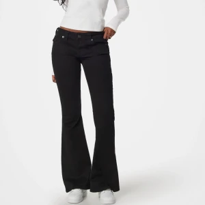 Svarta bootcut jeans från True Religion - Svarta jeans från True Religion med bootcut-snitt och klassiska fickor med lock och knapp bak. Byxorna är lågmidjade  och är tillverkade i mjukt jeansmaterial. Snygga detaljer vid midjan och bakfickorna ger en cool vibe.