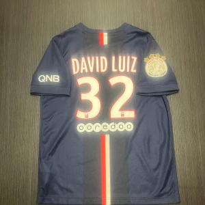 Äkta psg David luiz nummer 32 fotbollströja storlek 147-148 (12-13 år)!  - Säljer en mycket fin och sällsynt äkta David Luiz psg tröja nummer 32! Den har ligue 1 Champions patch! Tröjan är i väldigt väldigt fint skick/nyskick! Storlek 147-158 12-13 år!  Hör av dig vid minsta lilla fundering och kolla gärna in mina andra artiklar!