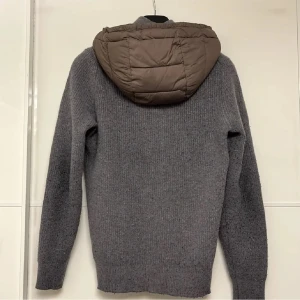 Grå stickad cardigan från Massimo Dutti - Säljer en grå sällsynt cardigan från Massimo Dutti i extra fin ull. Tröjan har dragkedja framtill, långärmad modell och en vadderad brun huva som ger en cool kontrast. Perfekt för kyliga dagar när du vill vara både varm och snygg. Storlek m men passar som s