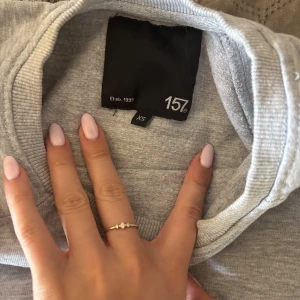 Grå sweatshirt från 157 XS - En basic ljusgrå sweatshirt från 157 i storlek XS. Tröjan har rund halsringning, långa ärmar och är tillverkad i mjuk bomullsmix. Perfekt för en chill och avslappnad stil. Använd få gånger.