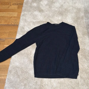 Mörkblå stickad tröja från Matinique - En stilren mörkblå stickad tröja från Matinique i storlek XL. Tröjan har rund halsringning och långa ärmar, perfekt för lager-på-lager. Materialet är mjukt och ger en clean look som funkar till jeans eller chinos.