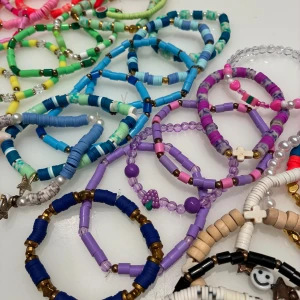 30 egenpärlade armband  - Säljer 30 st handgjorda armband i alla möjliga färger som blå, lila, rosa, grön, gul, röd, svart och vit. Armbanden är gjorda av töjbar plasttråd och olika pärlor och berlocker i massor av färger!!