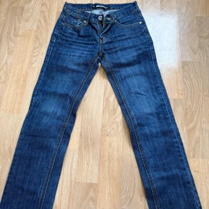 Blå jeans från Lab Industries stl 128 - Snygga blå jeans från Lab Industries med klassisk femficksdesign och dragkedjor på bakfickorna. Jeansen har raka ben och kontrastsömmar, perfekt för en cool och avslappnad stil. Materialet är slitstarkt denim i bomull.