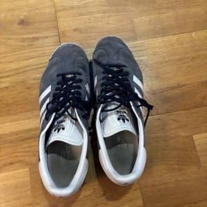 Adidas Gazelle mörkblå sneakers - Hej säljer nu mina adidas gazelle skor, de är 1 år gamla och har lite smuts och färgen har gått bort lite, men det mesta smutset går att tvätta bort. Annars är de i bra skick. Du får både de blåa och vita skosnören med dig.  Storlek: 48