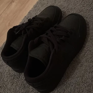 Svarta Nike Jordan 1 Low sneakers - Ett par helsvarta Nike Jordan 1 Low. Är i bra skick. Storlek 38,5 