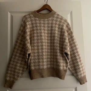 Beige och vit rutig stickad tröja - Mysig stickad tröja i beige och vitt med mönster. Nästan i nytt skick då den knappt varit använd. Från H&M storlek M
