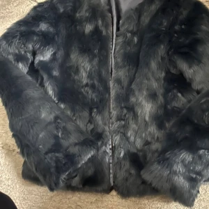 Mörkblå pälsjacka från Lindex - Mysig mörkblå pälsjacka från Lindex i storlek 158/164. Jackan har långärmad design, mjukt fuskpälsmaterial och stängs med dragkedja framtill. Perfekt för dig som vill ha en cool och trendig look under kyliga dagar.