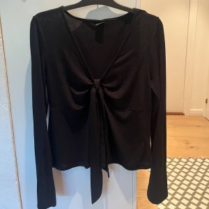 Svart långärmad topp med knyt Gina Tricot - Svart långärmad topp från Gina Tricot i storlek XL. Toppen har v-ringning och en knytning framtill. Den är använd fåtal gånger och är i bra skick. 
