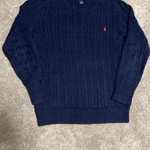 Mörkblå stickad tröja Polo Ralph Lauren - 🧶 Stilren stickad tröja från Polo Ralph Lauren i klassisk marinblå färg med den ikoniska loggan på bröstet 👕✨ Perfekt nu inför 🍂 hösten och ❄️ vintern – varm, bekväm och lätt att matcha både till vardags och mer uppklätt. 👌💙   XL i barn = S/M i herr storlek jag som är 171 och passar i S/M passar mig(kanske lite lite för stor)📏  Är nästan alldrig använd typ 5-7ggr då jag använde den varsamt.❤️  Vid mer info fråga mig bara(tex om mått)   Inga skavanker alls 🤩   100% bomull 🧶