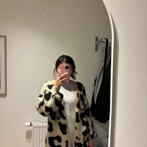 Beige och svart leopard cardigan jacka - Säljer en oversized  kofta i beige med svart leopardmönster. Koftan är långärmad, har en loose fit och är gjord i ett mjukt, stickat material. Perfekt för dig som vill ha en mysig och trendig look med lite edge, från NAKD, köpt på Vinted .