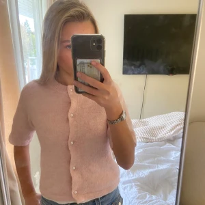 Ljusrosa kofta från Gina Tricot - Supersöt ljusrosa kofta från Gina Tricot med kort ärm och pärlknappar framtill. Koftan är stickad, Går både bra med linne och t-shirt under. Knappt använd