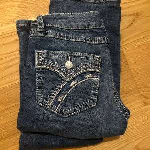 Blå jeans med broderad bakficka - Säljer dessa jeans i storlek 170 från Gina Young 💗! Aldrig använda, men har dock några trådar på ena fickan som har gått upp, går att se på en av bilderna. (Det var så när jag köpte dom).  Fickorna på rumpan är vanliga fickor med detaljer. 