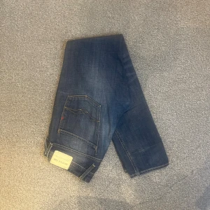 Replay Anbass jeans W28/L32 - Replay Anbass jeans i storlek W28/L32. Mörkblå denim med skön passform och lite stretch som gör dem bekväma. Bra skick utan hål eller fläckar, bara lite slitningar. Nypris runt 1500–2000 kr.  Mått: A (midja): 43 cm B (lårvidd): 27 cm C (fotvidd): 16 cm D (innerbenslängd): 80 cm  Säljes för 399 kr.  