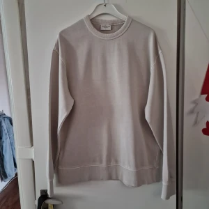 Beige sweatshirt från These Glory Days - En stilren beige sweatshirt från These Glory Days i storlek XL. Tröjan har rund halsringning, ribbade muddar och är tillverkad i mjuk bomull. Perfekt för en avslappnad och clean look. Använd 1 gång.