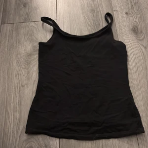 Svart linnetopp från Lindex XS - En enkel och stilren svart linnetopp från Lindex i storlek XS. Toppen har smala axelband och rak passform, perfekt att matcha med jeans eller kjol. Tillverkad i mjukt material som känns skönt mot huden.