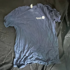 Blå Sea to Sky Gondola t-shirt Gildan - Mörkblå t-shirt från Gildan med Sea to Sky Gondola-tryck på bröstet och en stor gondol-grafik på ryggen. Klassisk passform med rund hals och korta ärmar. Tillverkad i mjuk bomull, perfekt för dig som gillar outdoor-vibes.