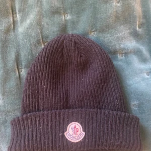 Moncler Mössa - En moncler beanie som är köpt 2023 och relativt använd men har för mesta dels bara varit använd på vintern. Skick 8/10. NFC Scan finns. Perfekt för vintern 