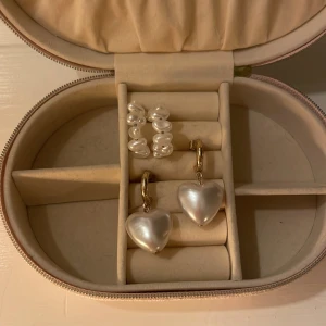 Två par örhängen med pärlor och hjärtan - Säljer två par jättefina örhängen! Ett par med bara pärlor och det andra paret med ett stort vitt hjärta. Säljer för att jag inte änvänder guld. Ej riktigt guld! Örhängena med ett stort vitt hjärta är fån Kappahl och dom med bara pärlor vet jag tyvärr inte. Båda paren kostar 60 kr var+ frakt!. Skriv för fler bilder.