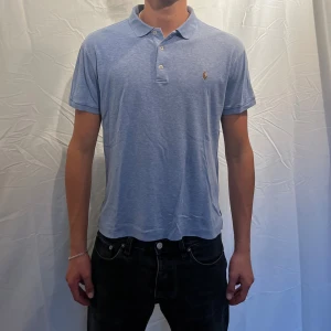 Pikétröja från Ralph Lauren - Sjukt Snygg ljusblå/babyblå pikétröja från Ralph Lauren. Klassisk krage med tre knappar och broderad logga på bröstet. Tillverkad i mjuk bomull, perfekt för en clean och stilren look. Modellen är 180cm. Storlek M men skulle säga att den passar bättre för S