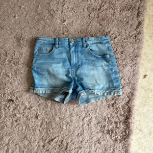 Blå jeansshorts från LAB Industries - Snygga ljusblå jeansshorts från LAB Industries med klassisk femficksdesign och uppvikta benslut. Shortsen har knapp och dragkedja framtill samt bälteshällor. Tillverkade i hållbar denim, perfekta för varma dagar.