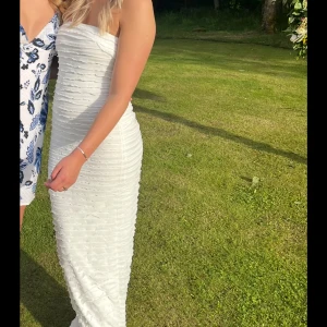 Vit långklänning med struktur - Säljer en vit långklänning med snygg struktureffekt och axelbandslös design. Klänningen har en figurnära passform och är perfekt för somriga tillfällen. Enkel men ändå elegant look som sticker ut med sin unika textur. Storlek S- köpt från Nelly