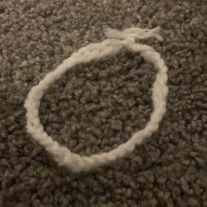 Handgjort vitt armband i ullgarn - Säljer ett enkelt handgjort armband i vitt ullgarn.  Perfekt för dig som gillar unika och personliga accessoarer.