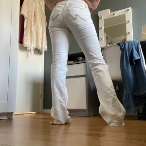 Nelly jeans - Säljer ett par vita jeans med bootcut-modell och snygga broderade detaljer på bakfickorna. Jeansen har låg midja och klassisk femficksdesign. Perfekta för dig som vill sticka ut med en fräsch och stilren look.