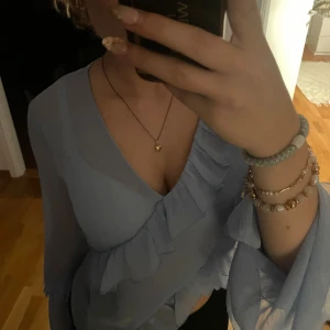 Ljusblå omlottblus med volanger - Supersöt ljusblå omlottblus med v-ringning och volangdetaljer! Perfekt för en stilren look!🪼🤩