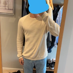 Beige stickad tröja från Selected Homme - Snygg beige stickad tröja från Selected Homme i storlek M/L perfekt för hela året. Tröjan har en rund halsringning och ett diskret ribbat mönster som ger en schysst struktur. Långärmad och med normal passform och även bra skick.