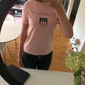 Rosa t-shirt från Gant med tryck - Säljer en ljusrosa t-shirt från Gant med klassiskt tryck och kortärmad. Perfekt för dig som gillar stilrena looks! Endast använd 1 gång! Pris kan diskuteras!!